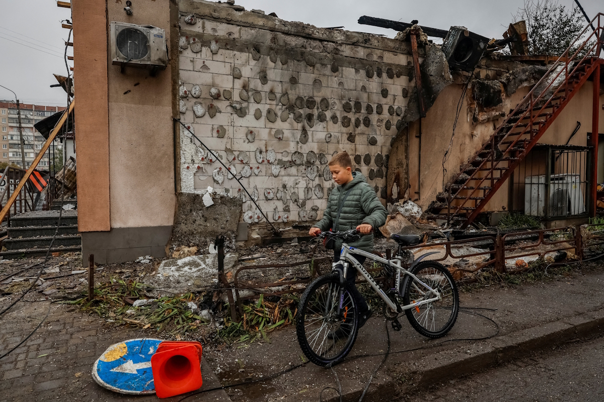 A bike boy passes in front of buildings that have suffered damage during Russian attacks with drones and rockets as part of the Russian invasion of Ukraine