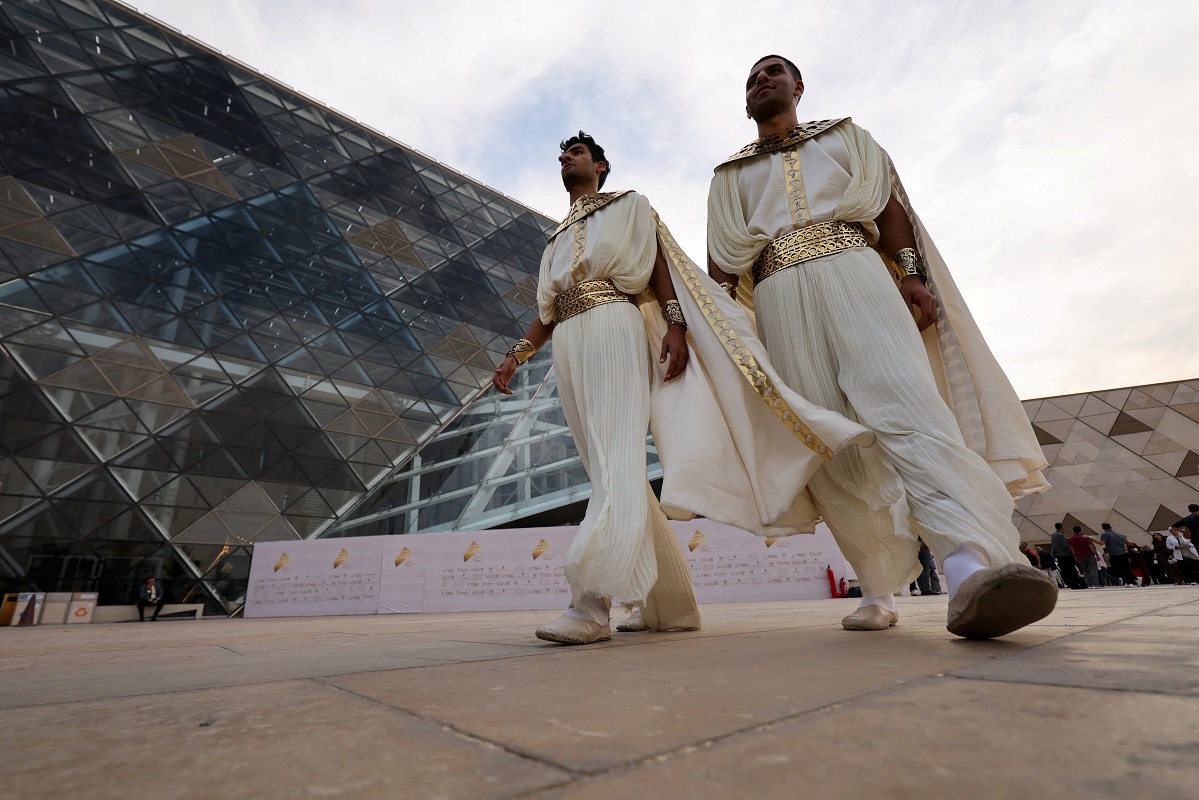 People wearing costiumes walk before the official opening of the Grand Egyptian Museum (GEM), near great Giza Pyramids, which will be attended by Egyptian President Abdel Fattah al-Sisi and other head state officials and key figures, in Giza, Egypt, November 1, 2025. REUTERS/Mohamed Abd El Ghany