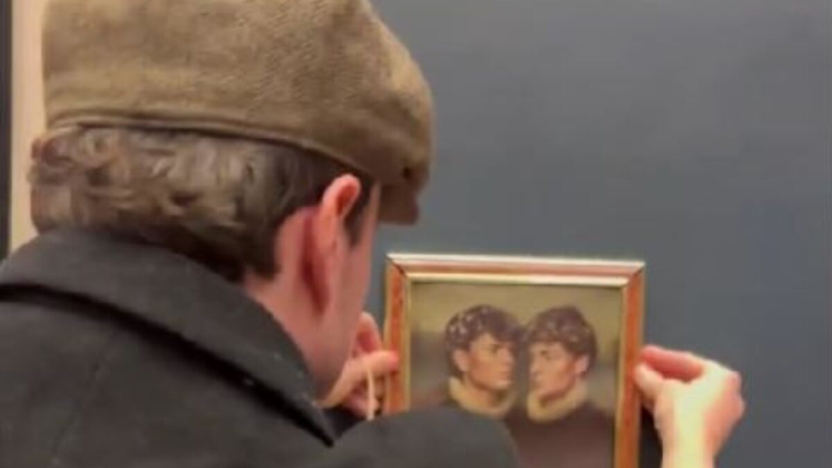 Άνδρας κρεμάει πίνακα σε τοίχο