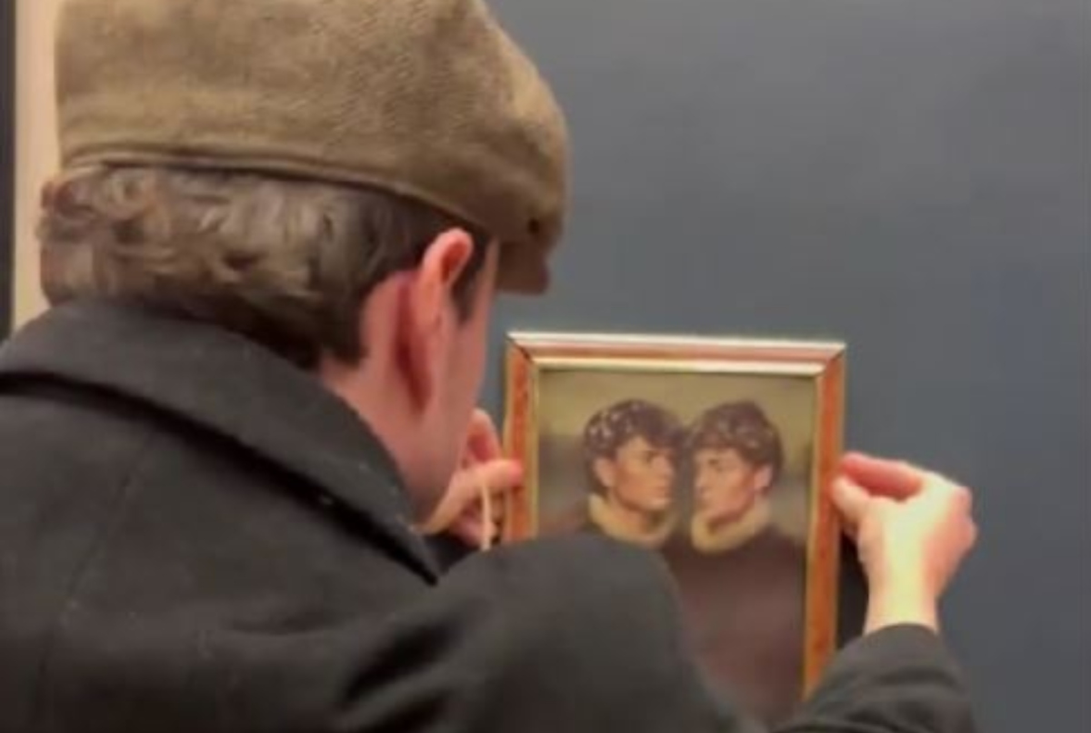 Άνδρας κρεμάει πίνακα σε τοίχο