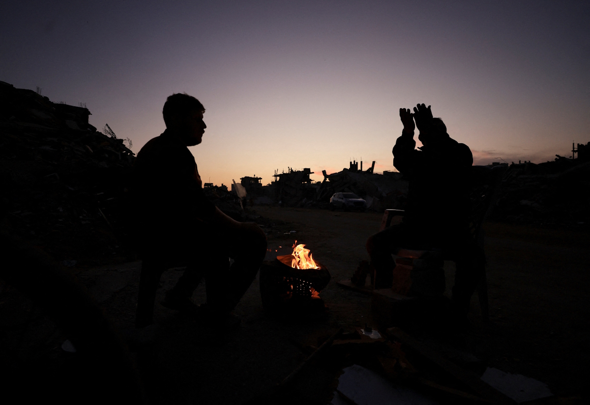 Παλαιστίνιοι ζεσταίνονται δίπλα σε φωτιά στη Γάζα