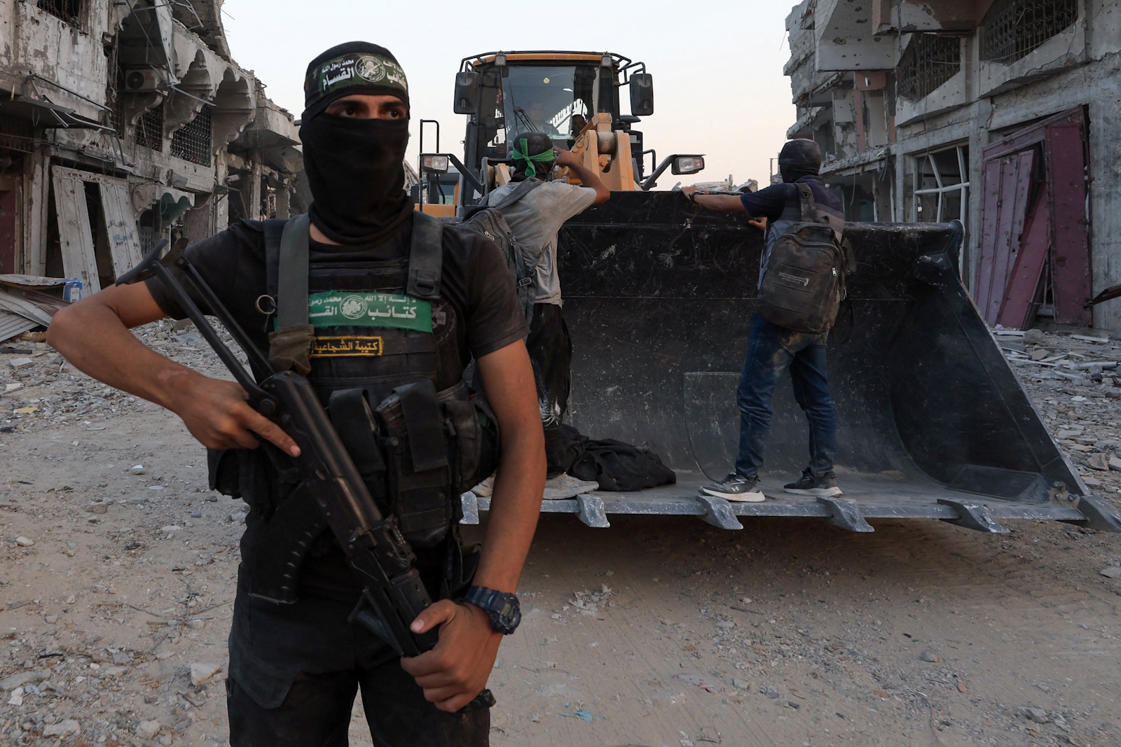 A Palestinian Hamas militant stands next to heavy machinery moving covered human remains, after Hamas said that it found the body of an Israeli hostage soldier on Tuesday and prepares to return it to Israel through the Red Cross, in Gaza City, November 4, 2025. REUTERS