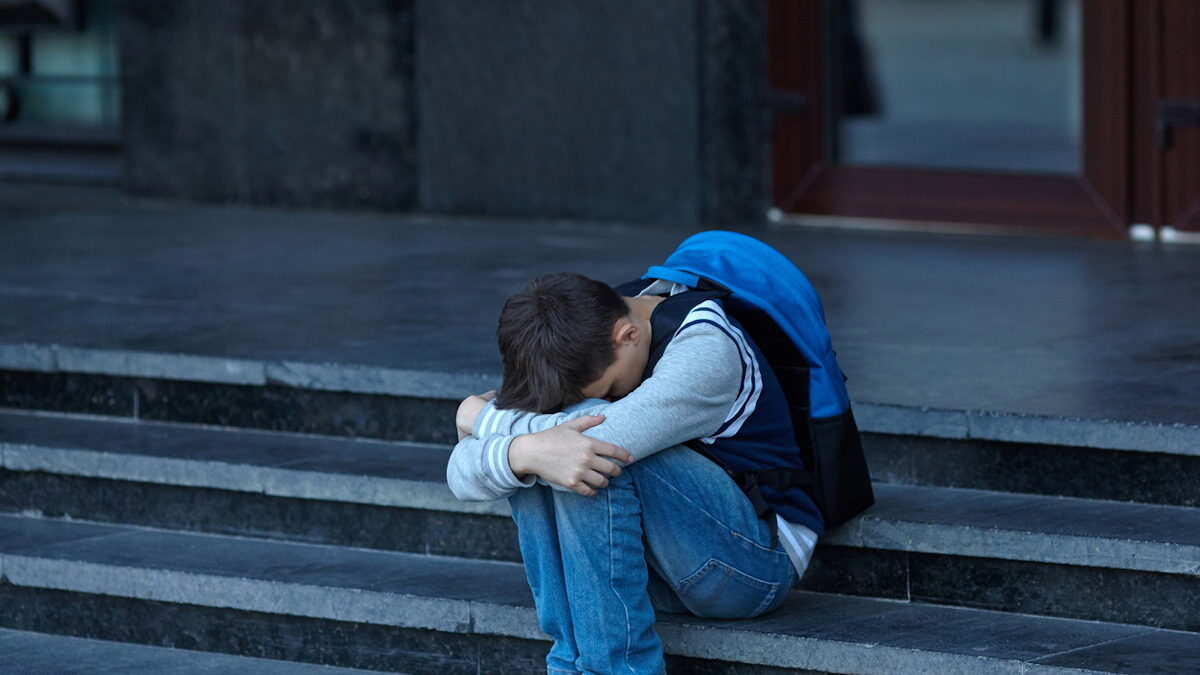 Schoolboy crying in the yard of the school. Negative emotion.