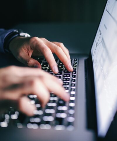 Close up of hands typing on laptop. Night work concept