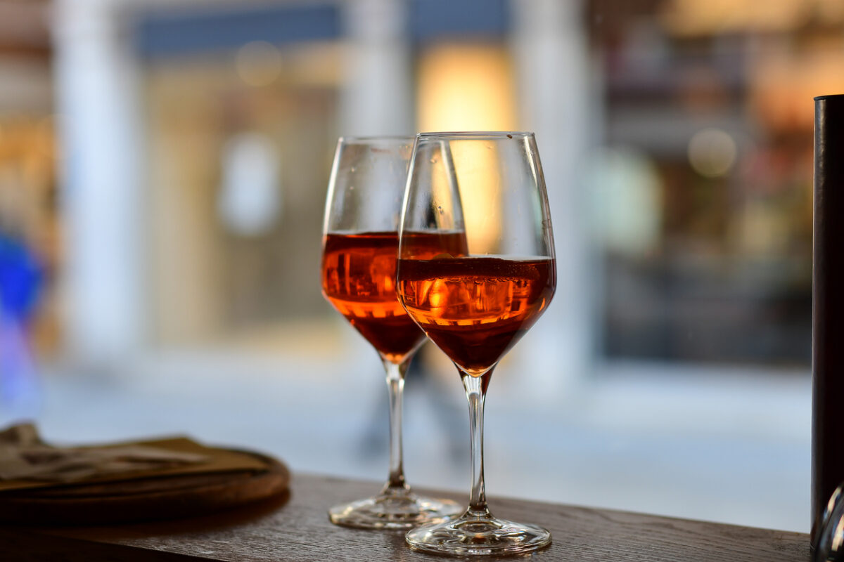 Сocktail aperitif Spritz with slice of orange in large round glasses on a wooden table in a bar in Italy. view through the bar window. selective focus