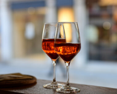 Сocktail aperitif Spritz with slice of orange in large round glasses on a wooden table in a bar in Italy. view through the bar window. selective focus