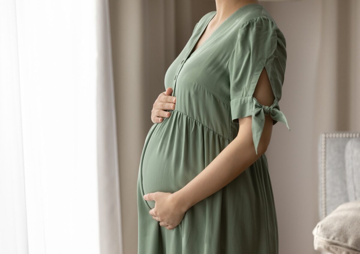 Expectant mother wearing dress for pregnant, holding big baby bump, feeling kicks, touching and hugging belly with love and care. Childbirth, pregnancy, clothes for expecting concept
