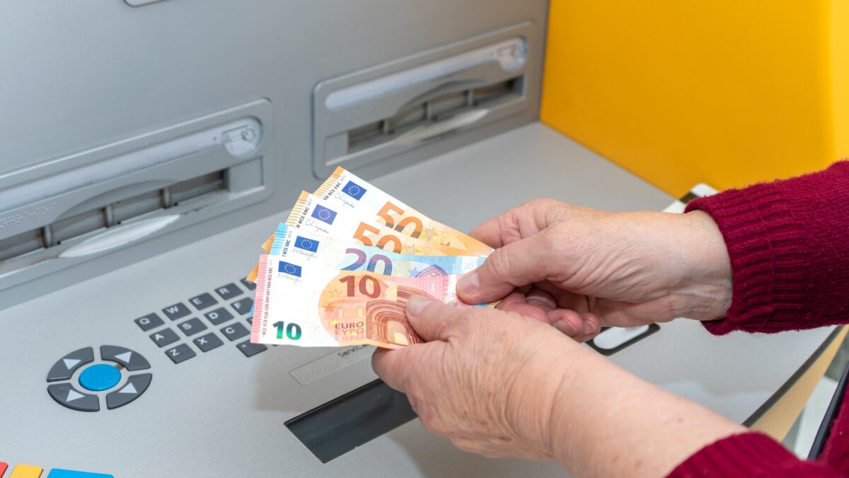 RETIRED SENIOR WOMAN WITHDRAWING MONEY FROM AN ATM. DIGITAL DIVIDE AMONG THE ELDERLY
