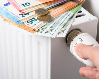 Hand adjusting the valve knob of heating room radiator temperature thermostat