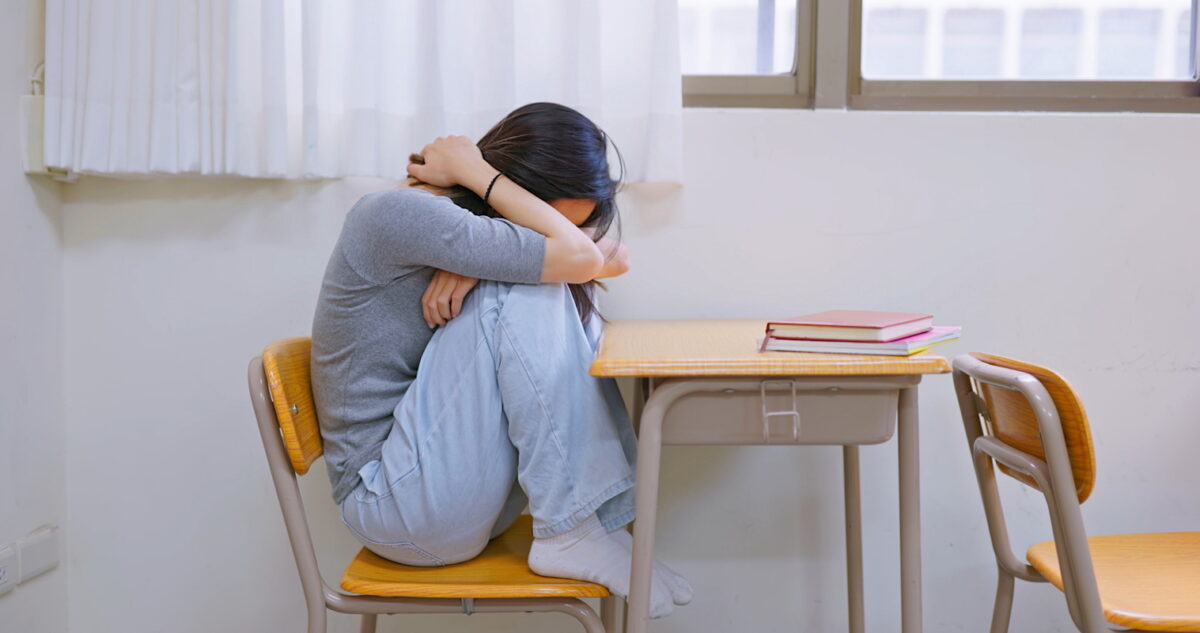 Asian female student is crying and depressed in classroom