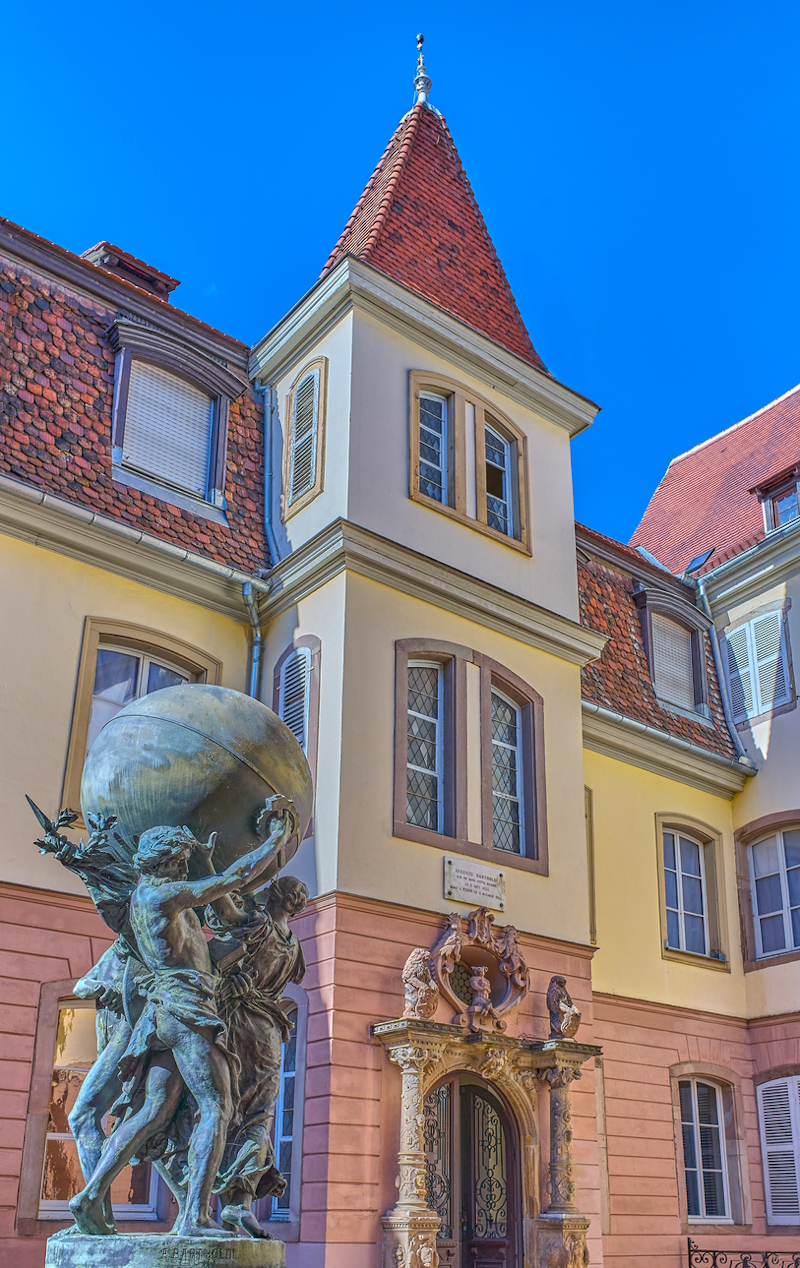 Colmar, France - September 21, 2022: The birthplace of Auguste Bartholdi with a work by the sculptor in the foreground
