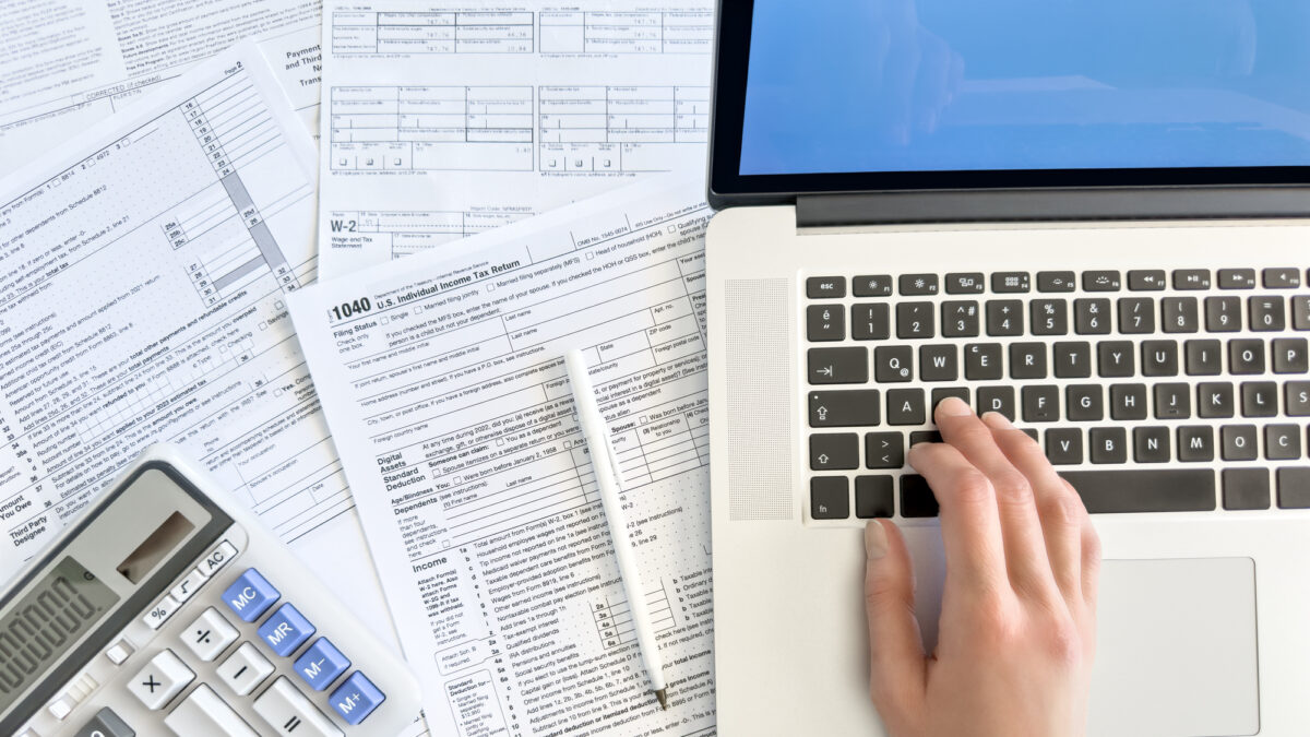 Close up photo of a woman doing taxes with laptop and tax forms in a house