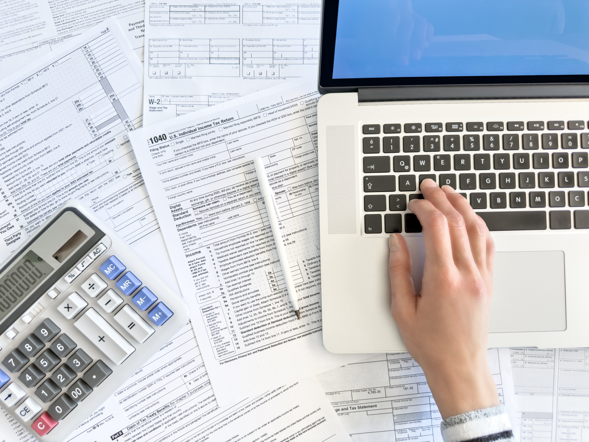 Close up photo of a woman doing taxes with laptop and tax forms in a house