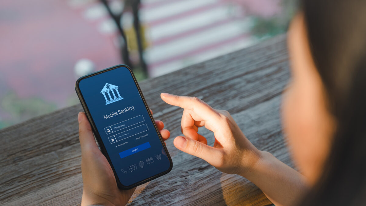 Online payment concept. Over shoulder view of a woman accessing a mobile banking app on her smartphone, highlighting the ease of digital finance management. Internet bank, money transaction, fintech,