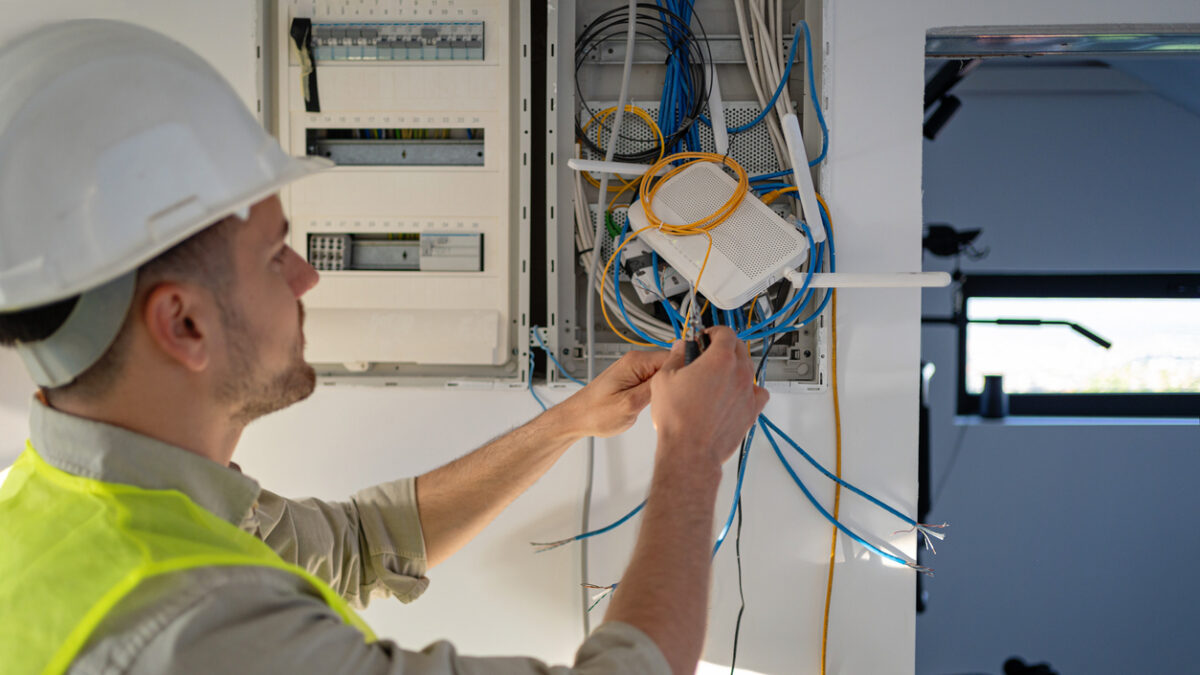 Young male Caucasian electrician working on the electrical installation of a new house, he is focused and dedicated to his work