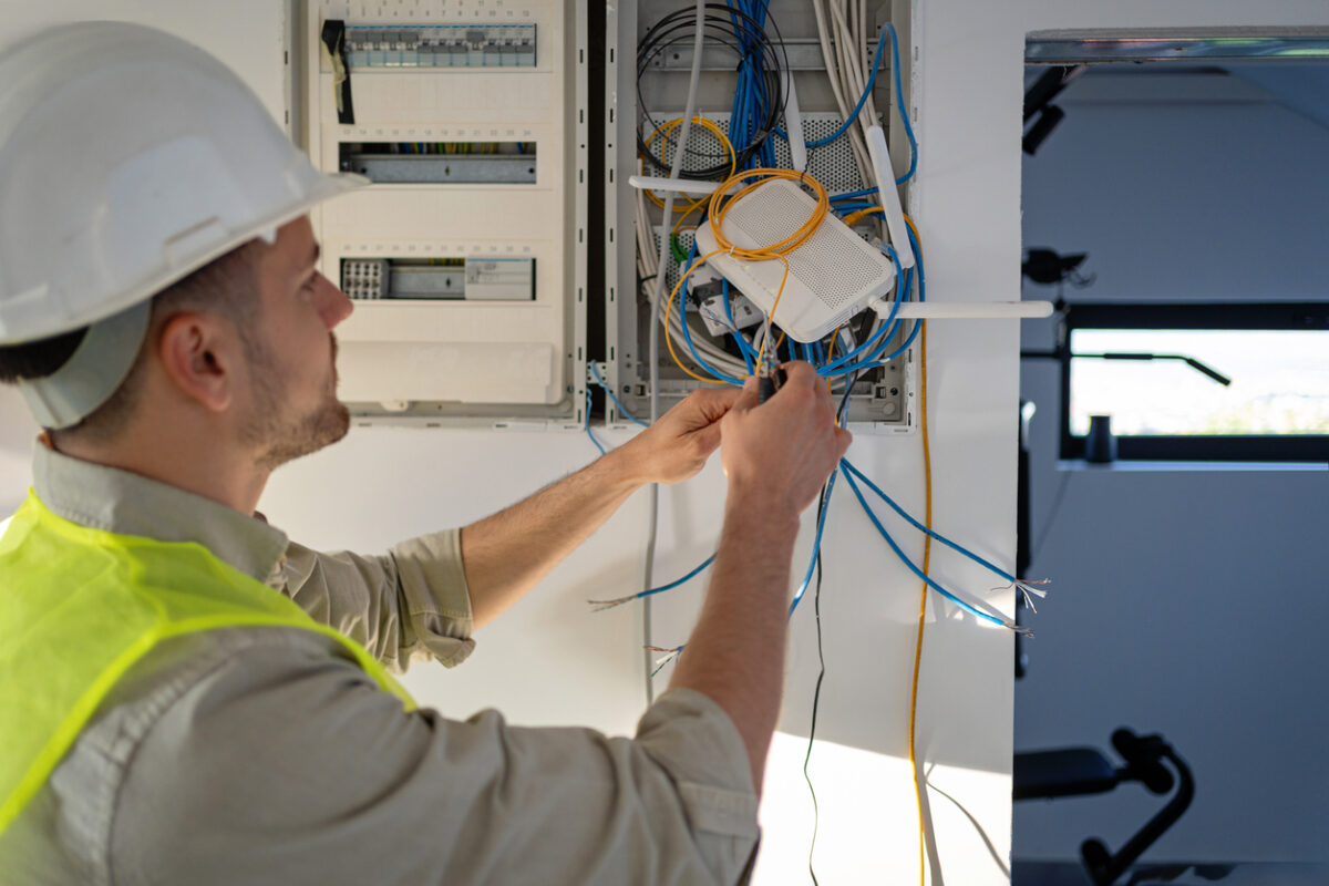 Young male Caucasian electrician working on the electrical installation of a new house, he is focused and dedicated to his work