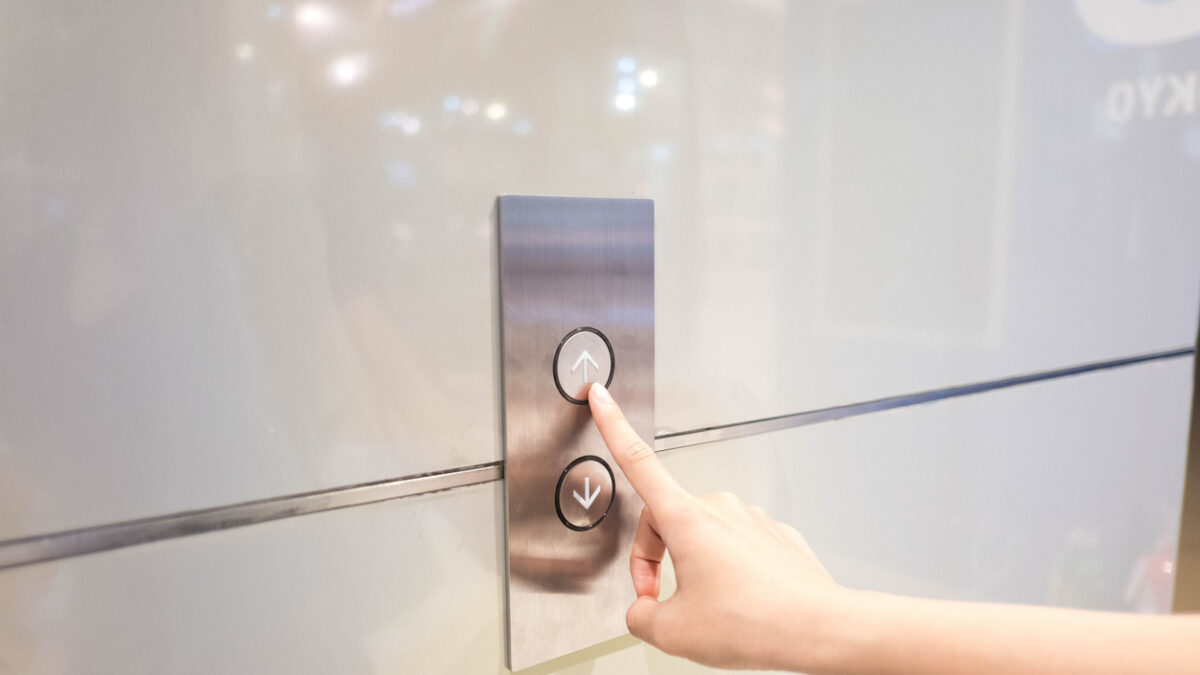 Cropped Hand Of Woman Pressing Push Button For Elevator On Wall