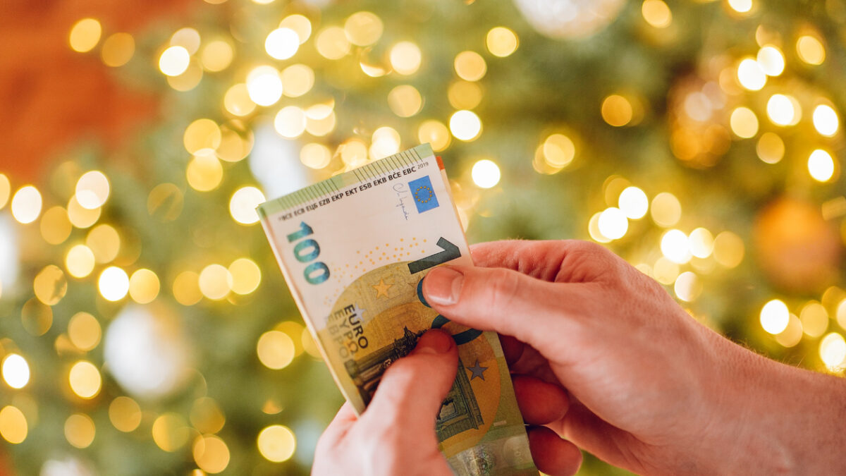 Euro banknotes and Christmas tree. hands counting euro banknotes on a Christmas tree background