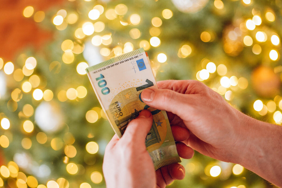 Euro banknotes and Christmas tree. hands counting euro banknotes on a Christmas tree background