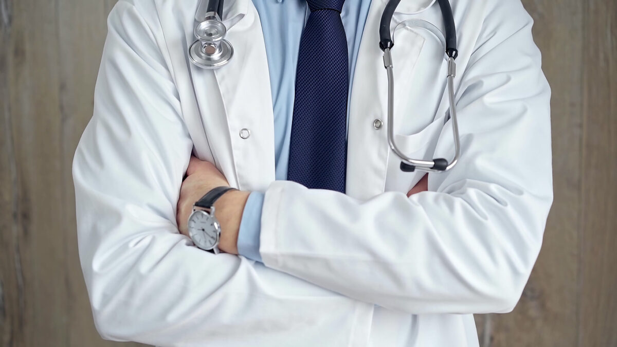 Close-up of a healthcare professional's torso wearing a lab coat and stethoscope. Crossed arms, Medicine.