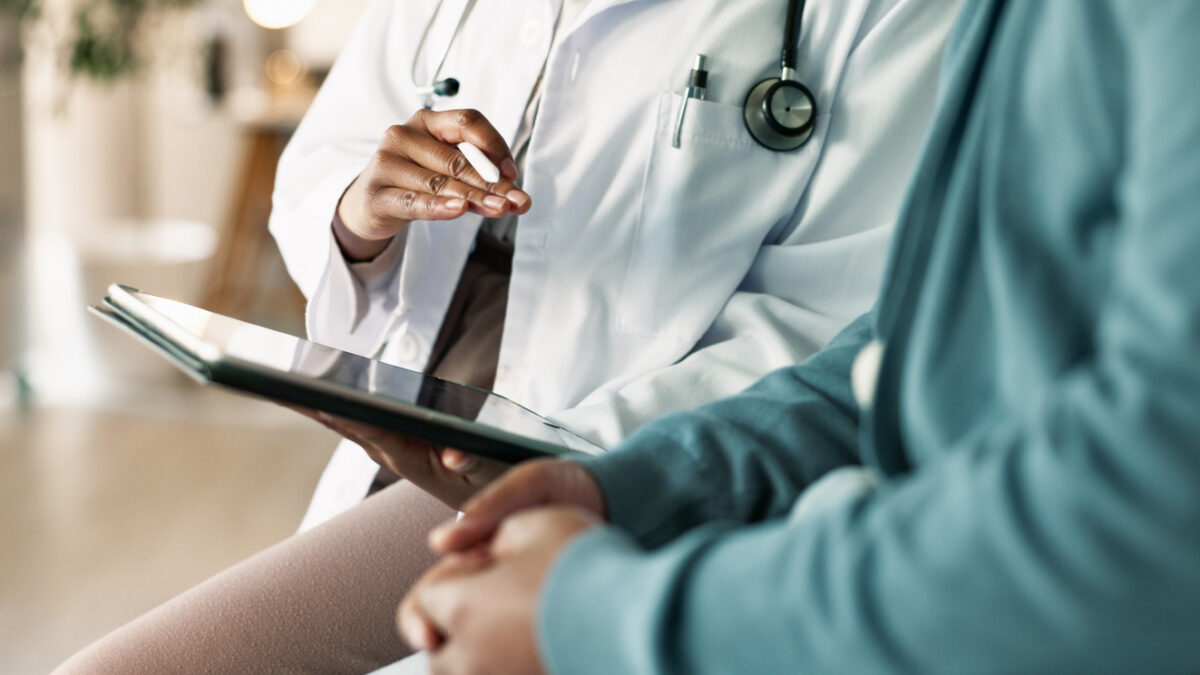 Tablet, hands and patient with doctor in hospital for consultation with cold, flu and sickness. Digital technology, conversation and person with healthcare worker for medical diagnosis in clinic.