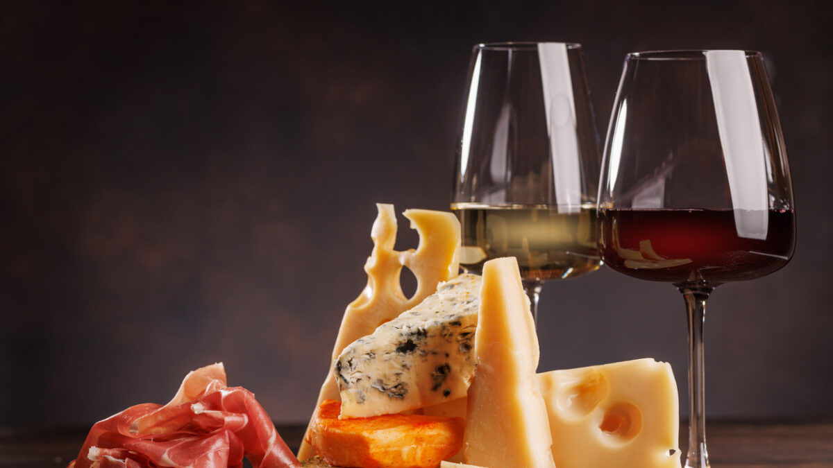 Assorted cheeses paired with glasses of wine on a rustic table, creating an elegant tasting setup