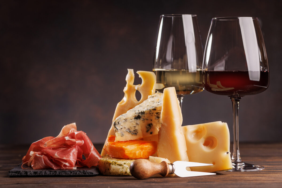 Assorted cheeses paired with glasses of wine on a rustic table, creating an elegant tasting setup