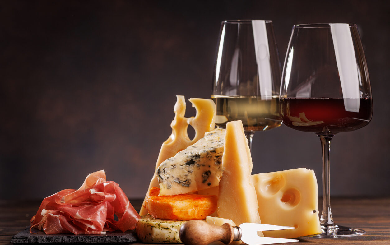 Assorted cheeses paired with glasses of wine on a rustic table, creating an elegant tasting setup