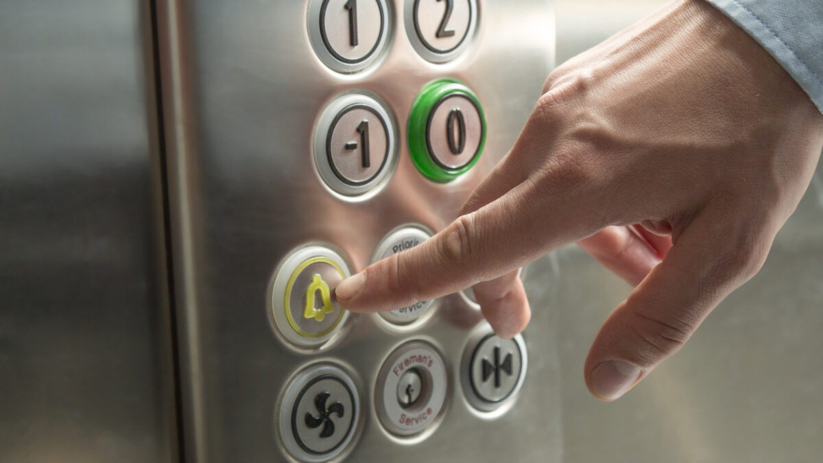 Hand pressing the alarm button in the elevator