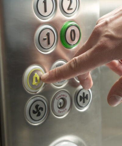 Hand pressing the alarm button in the elevator