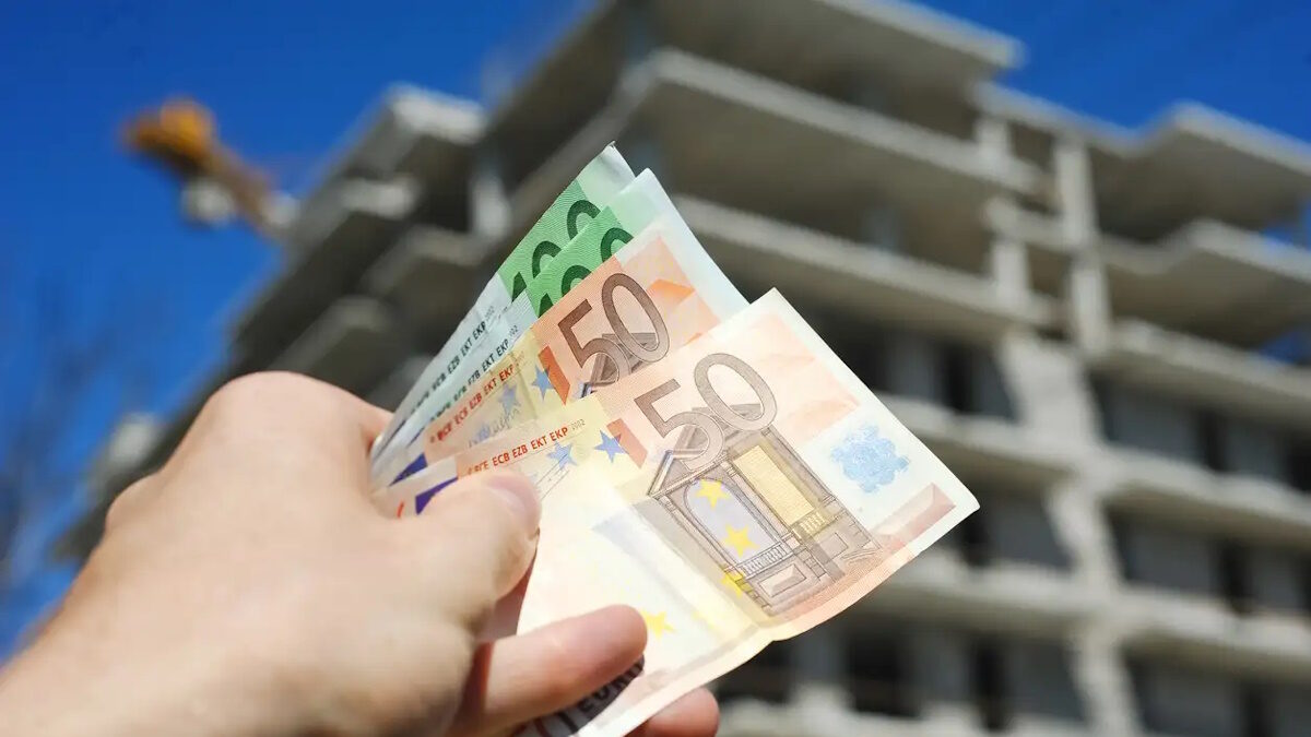 Man holding euro money in front of block building in build process