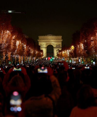 Πλήθος κόσμου απολαμβάνει τη φωταγώγηση κατά μήκος των Ηλυσίων Πεδίων, με την Αψίδα του Θριάμβου στο βάθος