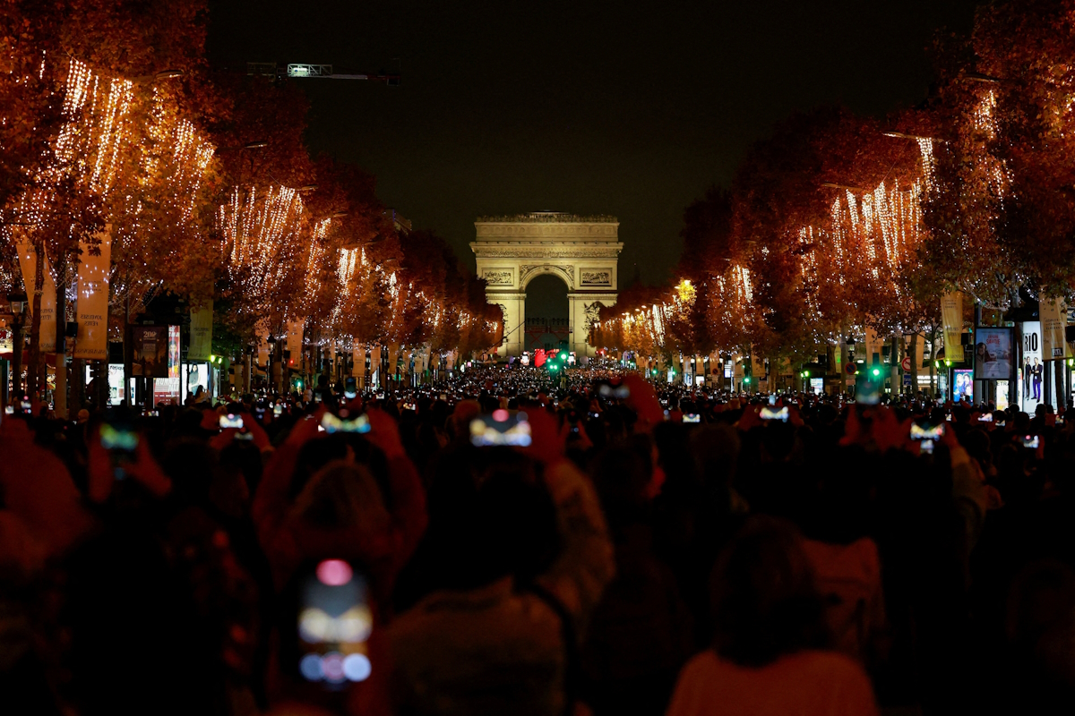 Πλήθος κόσμου απολαμβάνει τη φωταγώγηση κατά μήκος των Ηλυσίων Πεδίων, με την Αψίδα του Θριάμβου στο βάθος