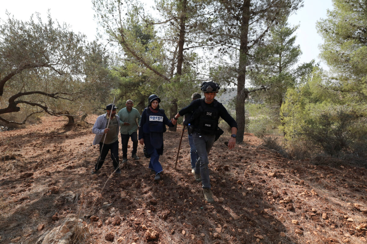 Ο σύμβουλος ασφαλείας του Reuters, Γκραντ Μπόουντεν, βοηθά τον φωτογράφο του Reuters, Ρανίν Σαουάφτα, μετά από επίθεση ισραηλινών εποίκων