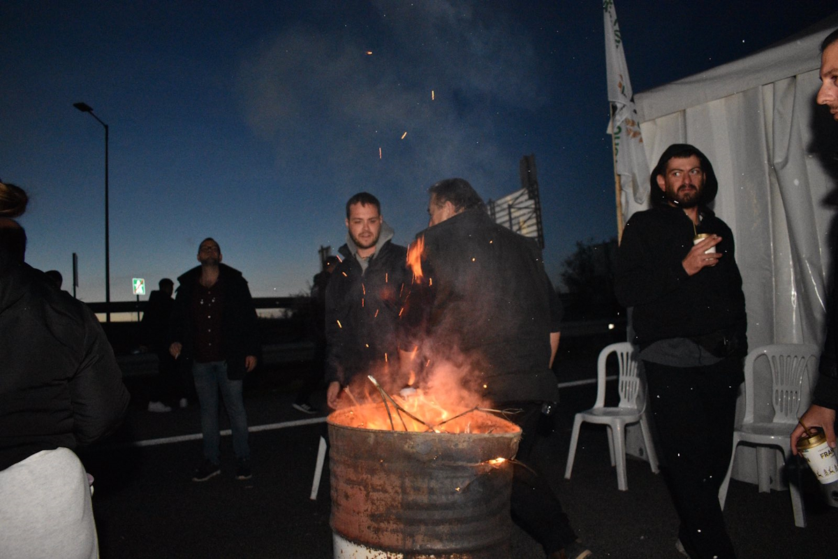 Αγρότες της Θεσσαλίας γύρω από τη φωτιά που άναψαν για να ζεσταθούν στη διάρκεια της νύχτας