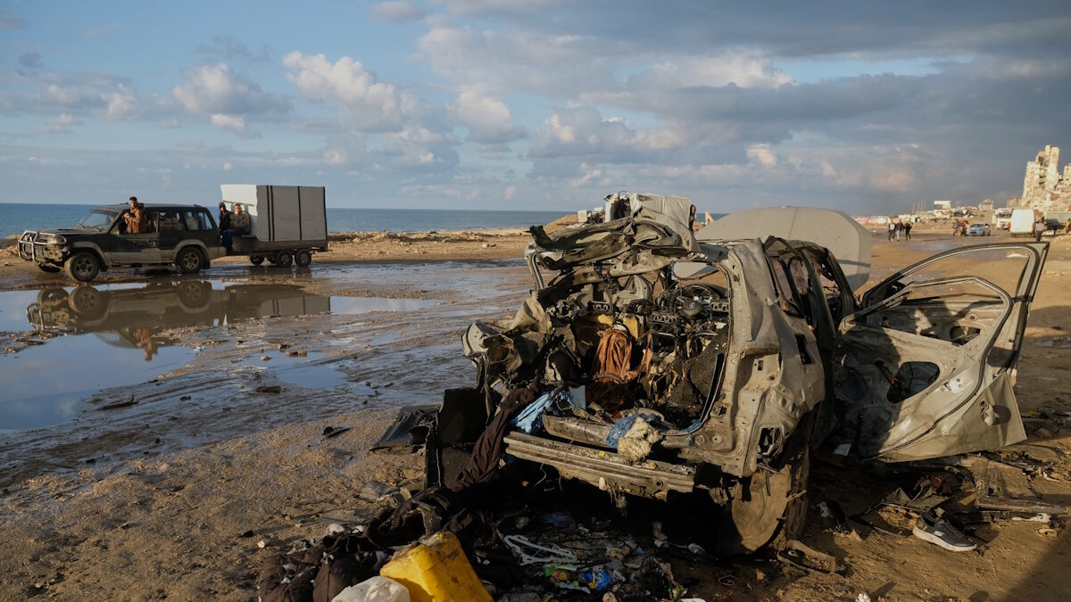Παλαιστίνιοι περνούν με το αυτοκίνητό τους δίπλα από ένα κατεστραμμένο αυτοκίνητο μετά από ισραηλινή επίθεση στην πόλη της Γάζας
