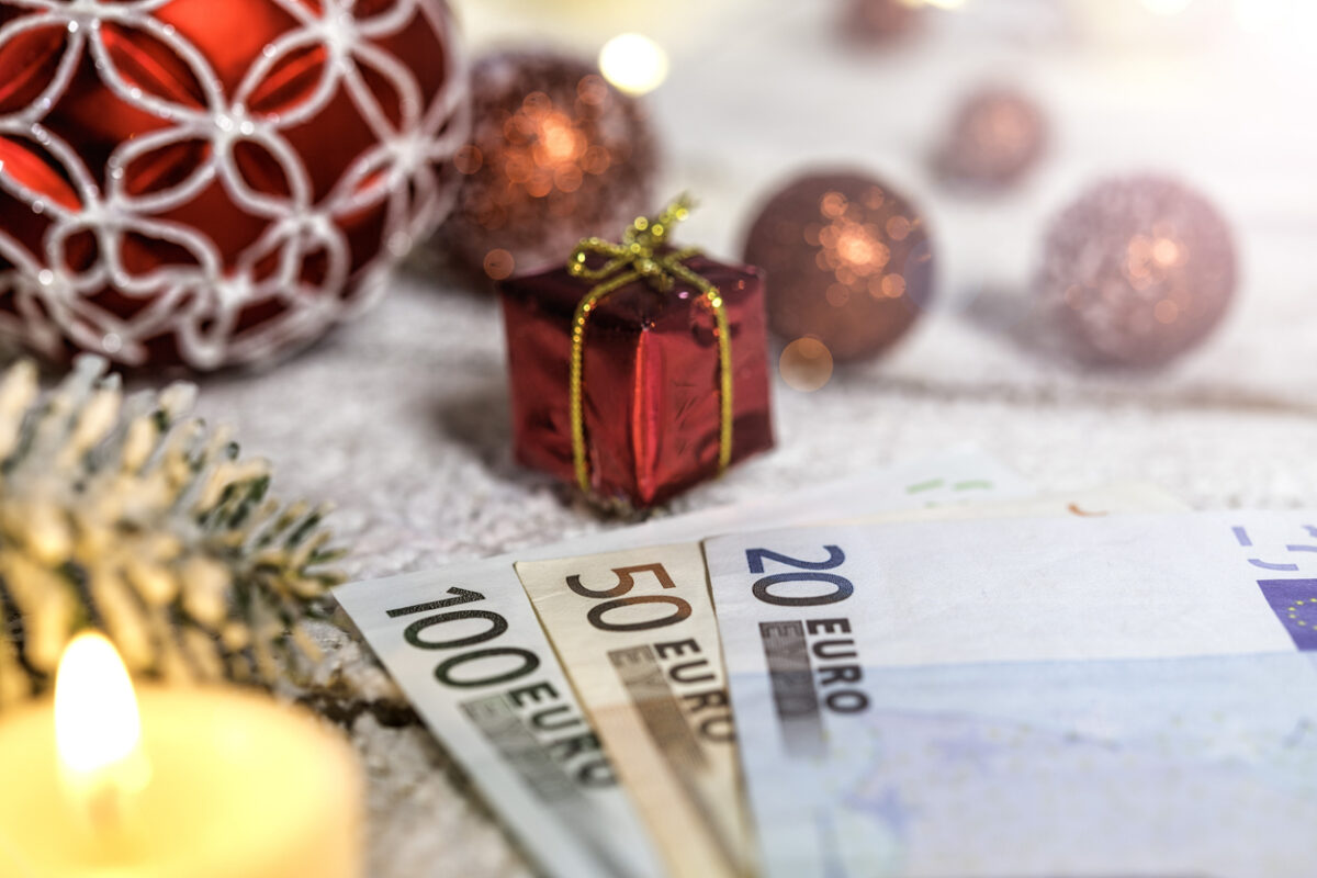 Christmas ball on old wooden table with candle and Euro banknotes