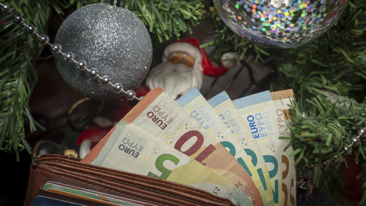Santa Christmas ornament seared in a metal chair under a Christmas with Euro banknotes in a conceptual image