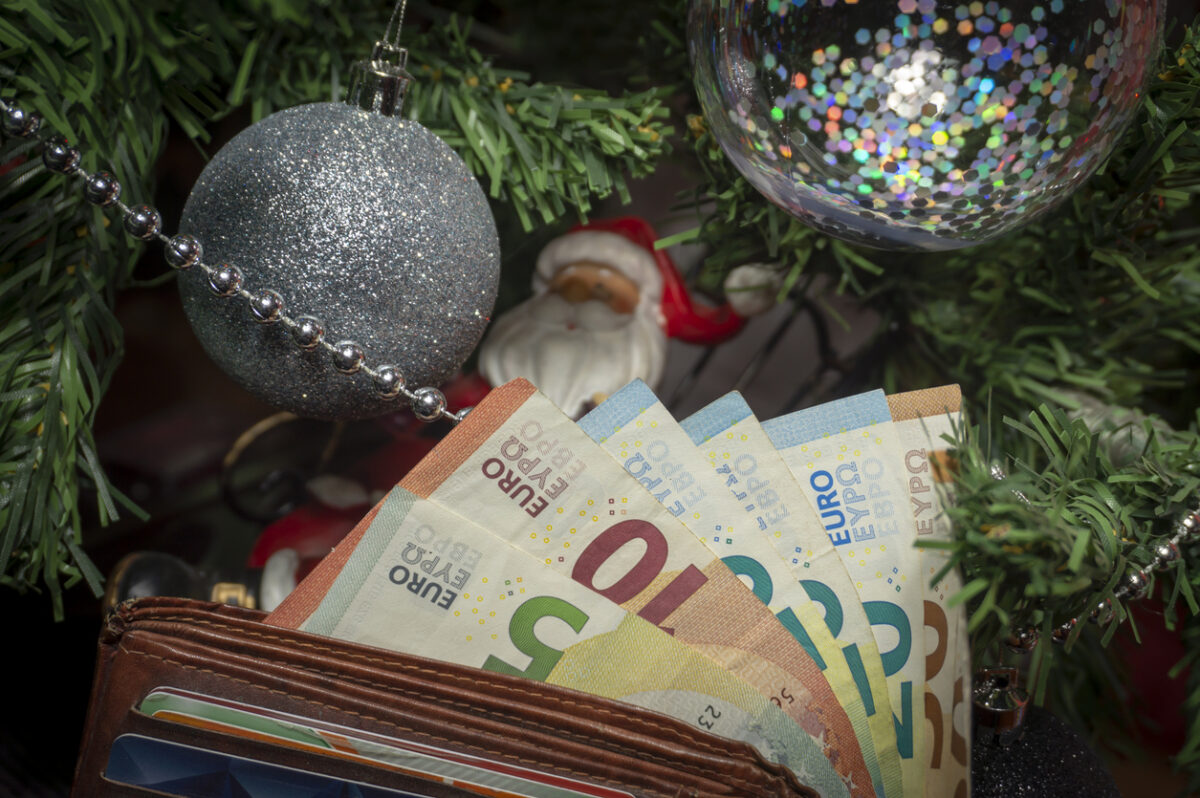 Santa Christmas ornament seared in a metal chair under a Christmas with Euro banknotes in a conceptual image