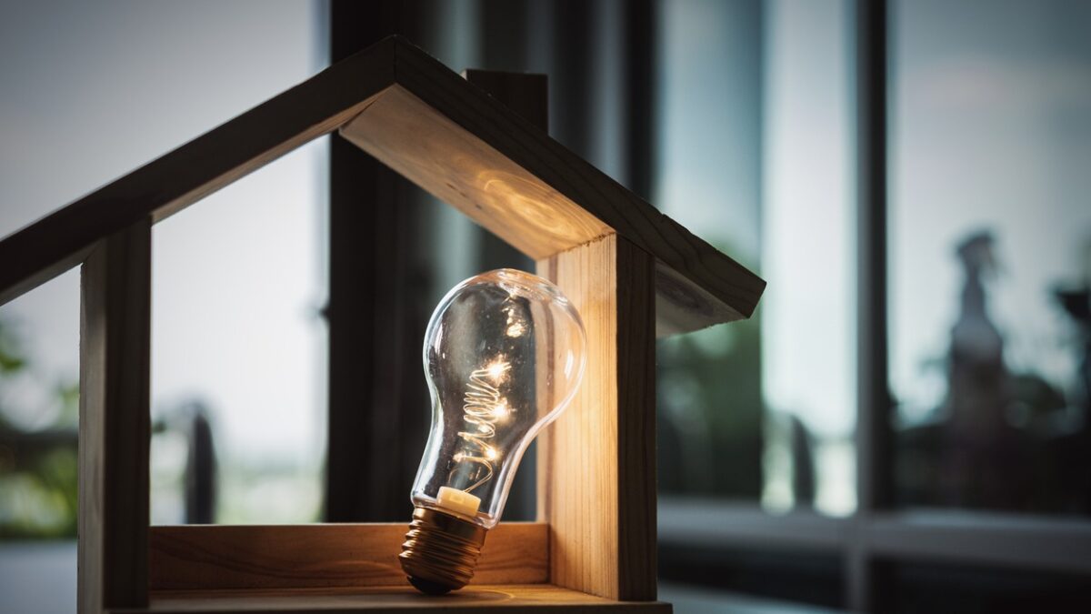 Light bulb with wood house on the table, a symbol for construction, Creative light bulb idea, power energy or business idea concept ecology, loan, mortgage, property or home.