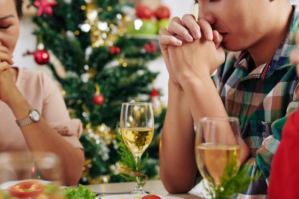 Cropped image of people praying before eating CHristmas dinner at home
