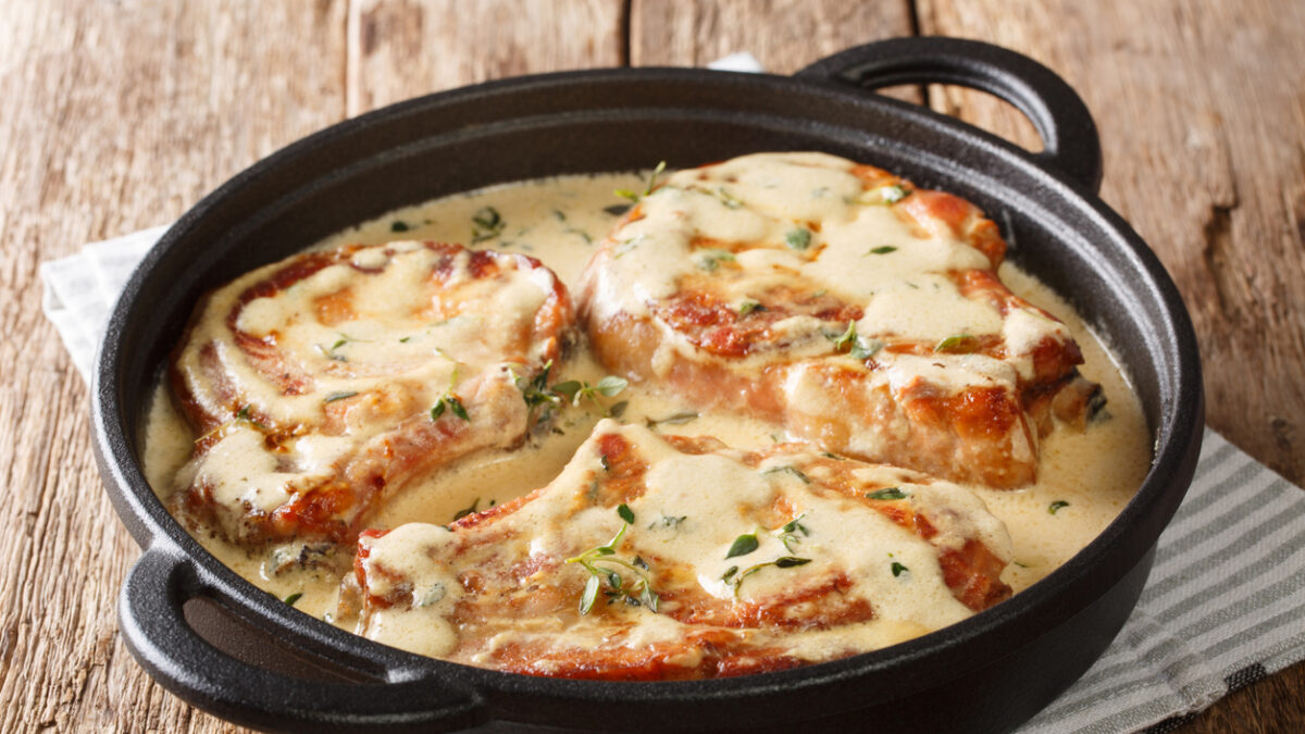 boneless pork chops served in creamy wine sauce with herbs close-up in a pan on the table. horizontal