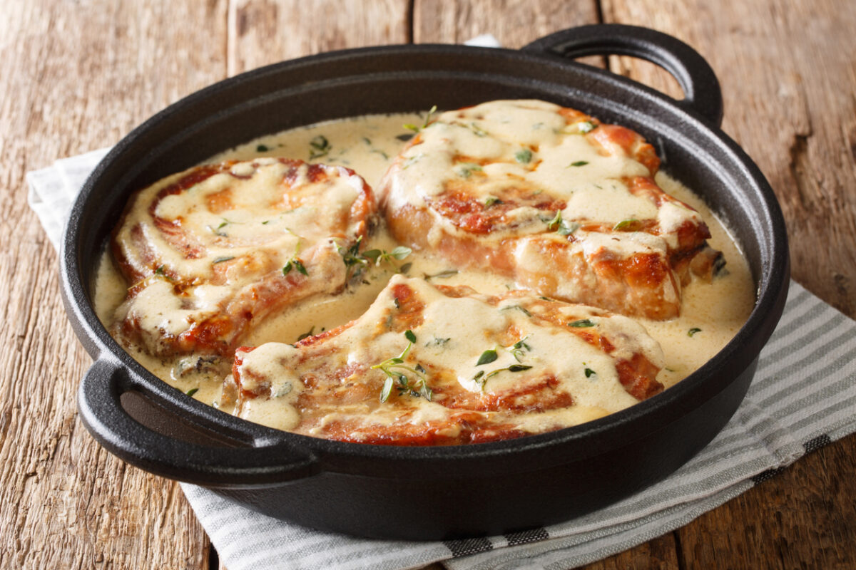 boneless pork chops served in creamy wine sauce with herbs close-up in a pan on the table. horizontal