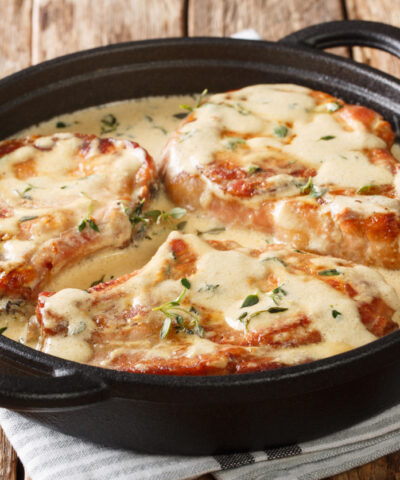 boneless pork chops served in creamy wine sauce with herbs close-up in a pan on the table. horizontal