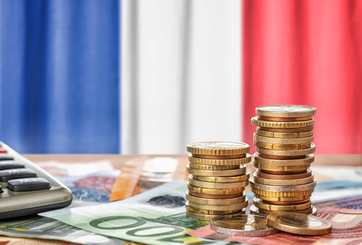 Euro banknotes and coins in front of the national flag of France