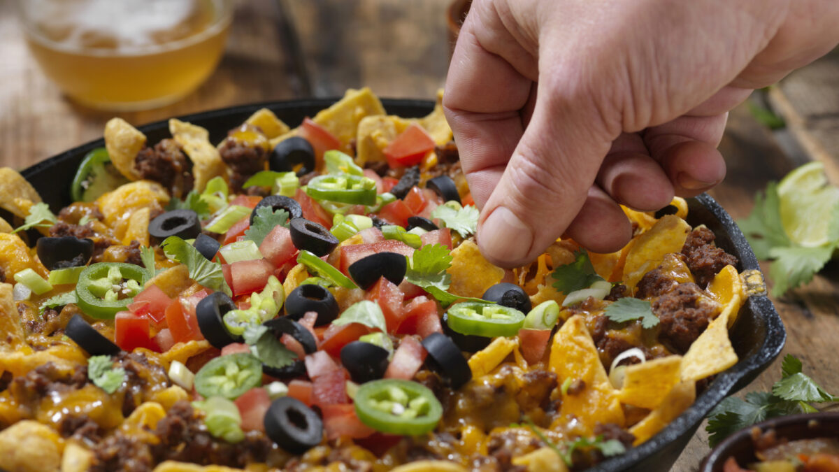 Baked Frito Pie (Chili Corn Chip Nachos) with Black Olives, Tomatoes, Green Onions, Jalapenos, Salsa, Guacamole and Sour Cream