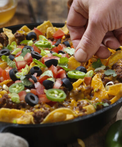 Baked Frito Pie (Chili Corn Chip Nachos) with Black Olives, Tomatoes, Green Onions, Jalapenos, Salsa, Guacamole and Sour Cream
