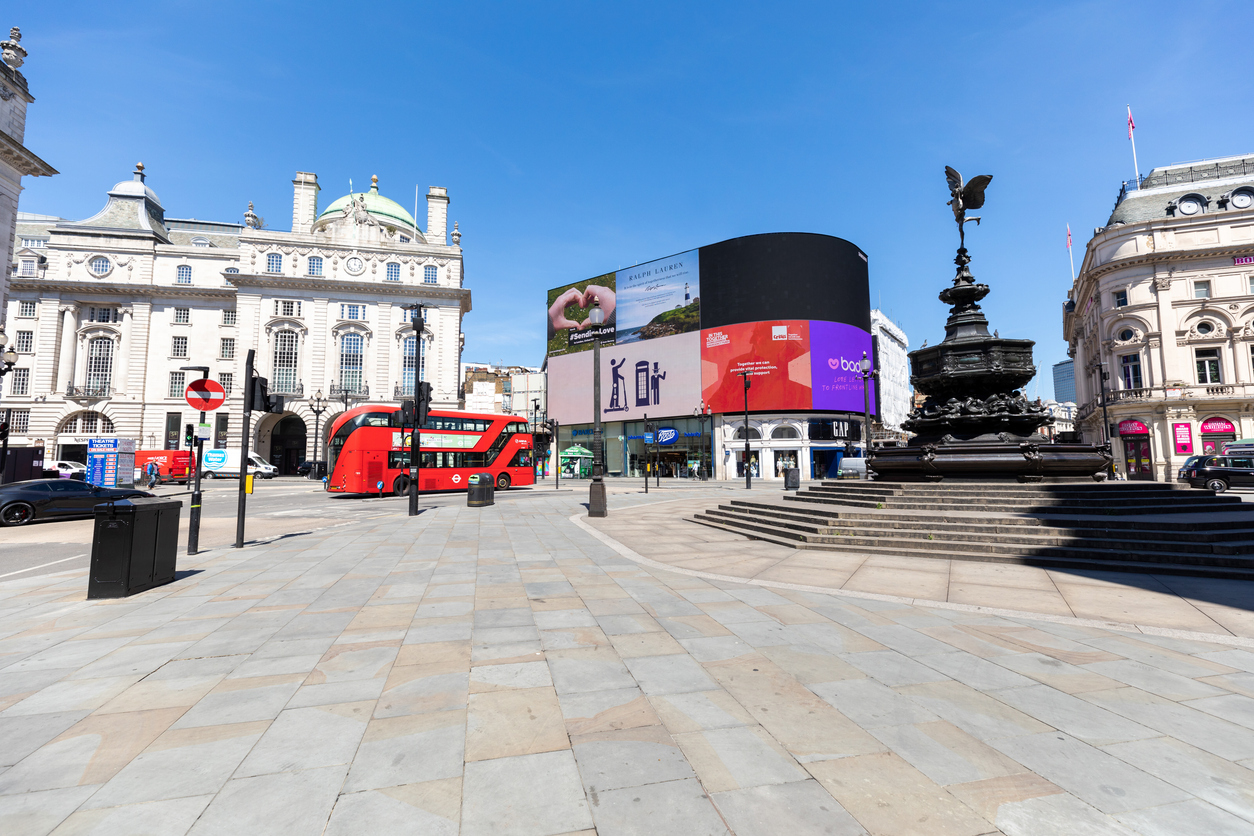 Empty Piccadilly circus in London during lockdown, one red double decker bus only on the street