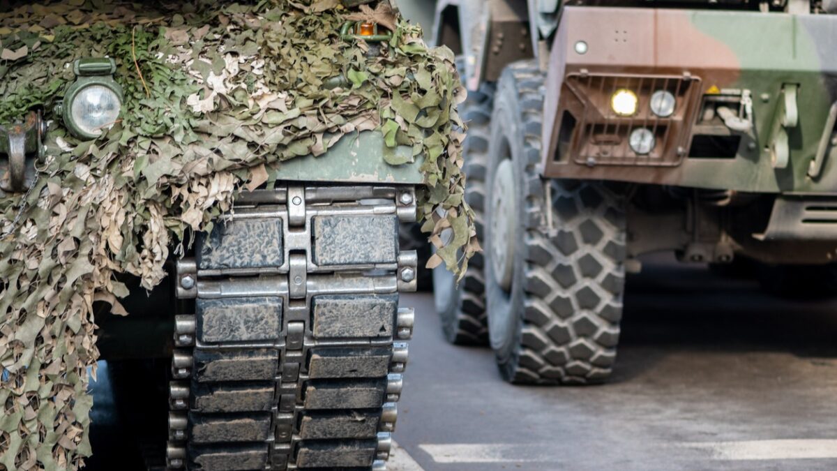 NATO or North Atlantic Treaty Organization armored crawler tanks and other military vehicles on the road of the city with soldiers