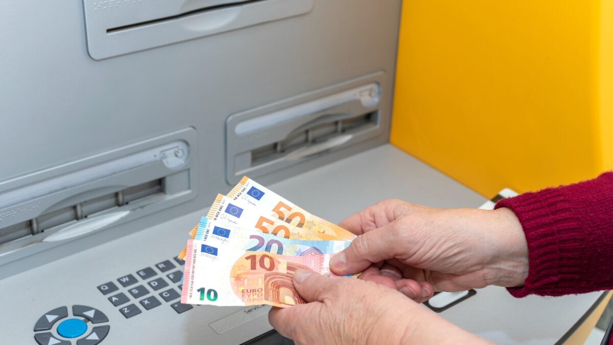 RETIRED SENIOR WOMAN WITHDRAWING MONEY FROM AN ATM. DIGITAL DIVIDE AMONG THE ELDERLY